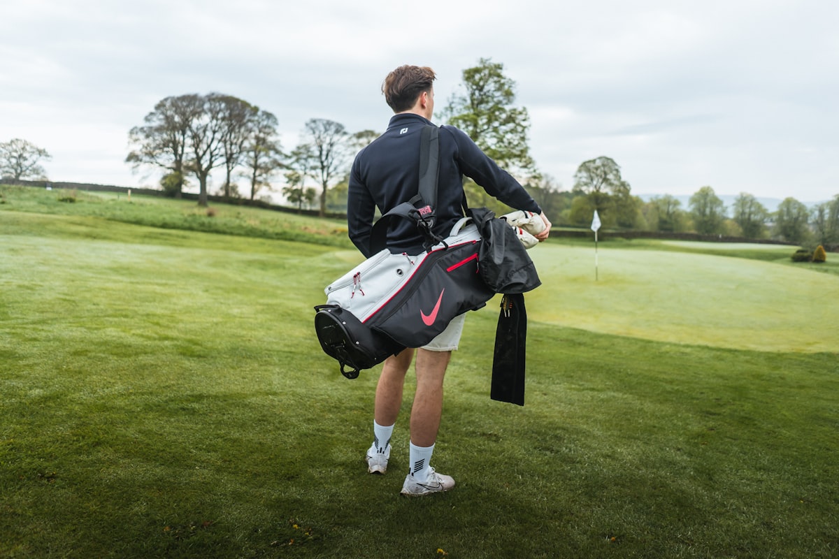 A golfer carrying a branded bag toward the green — equipment, footwear, and apparel logos are all part of the endorsement ecosystem