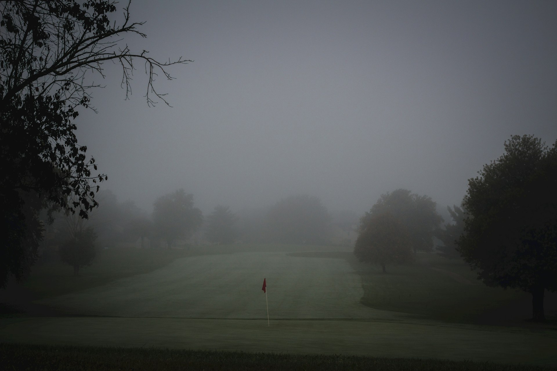 Misty golf course at dawn with flag pin