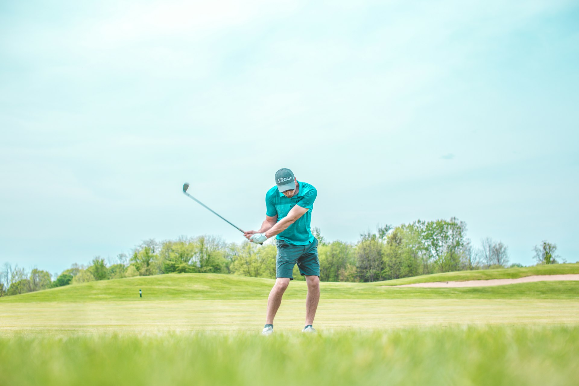 Golfer mid-swing on a bright fairway